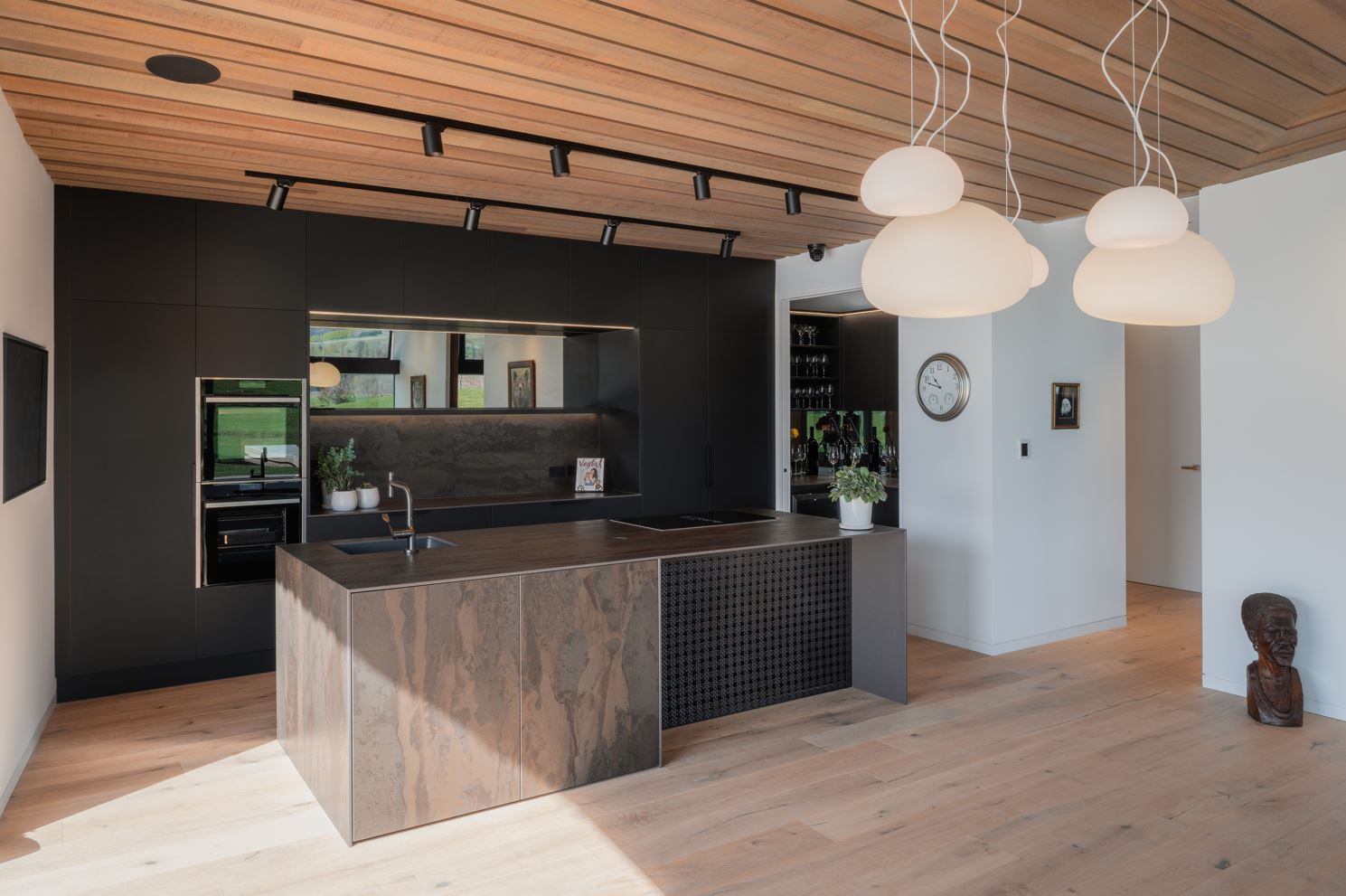 This kitchen, in Wings Over Water House in Queenstown by Kamermans Architects, is defined by a dark and moody material palette within a highly sculptural home. Image: David Straight