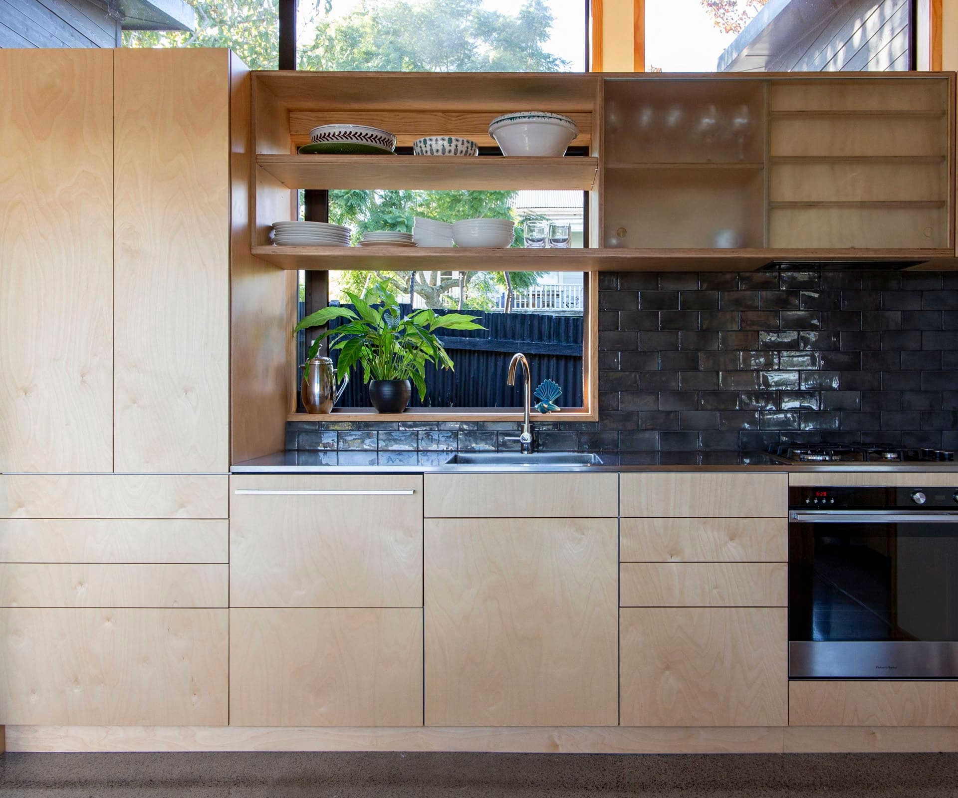 Small contemporary kitchen with wooden cabinetry and black tile splashback