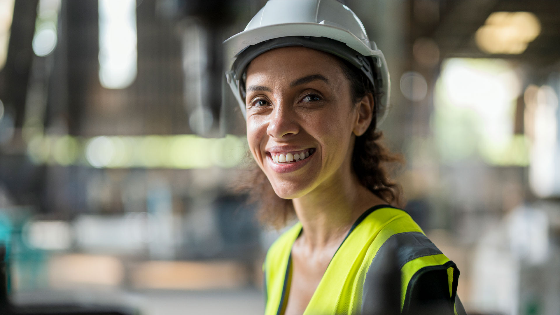 Employee on a construction site in a hard hat and high-vis vest.