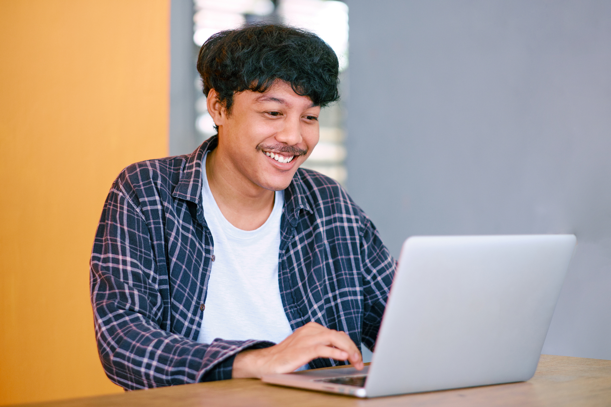 Young man smiling while typing on laptop