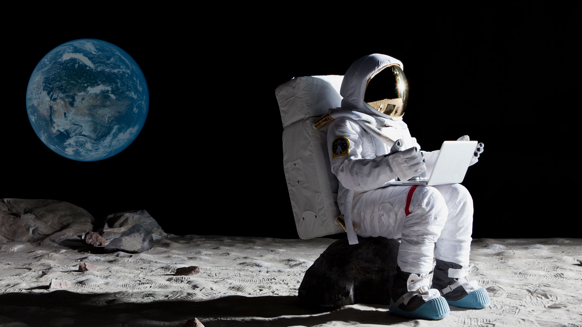 Astronaut working on the moon with laptop.