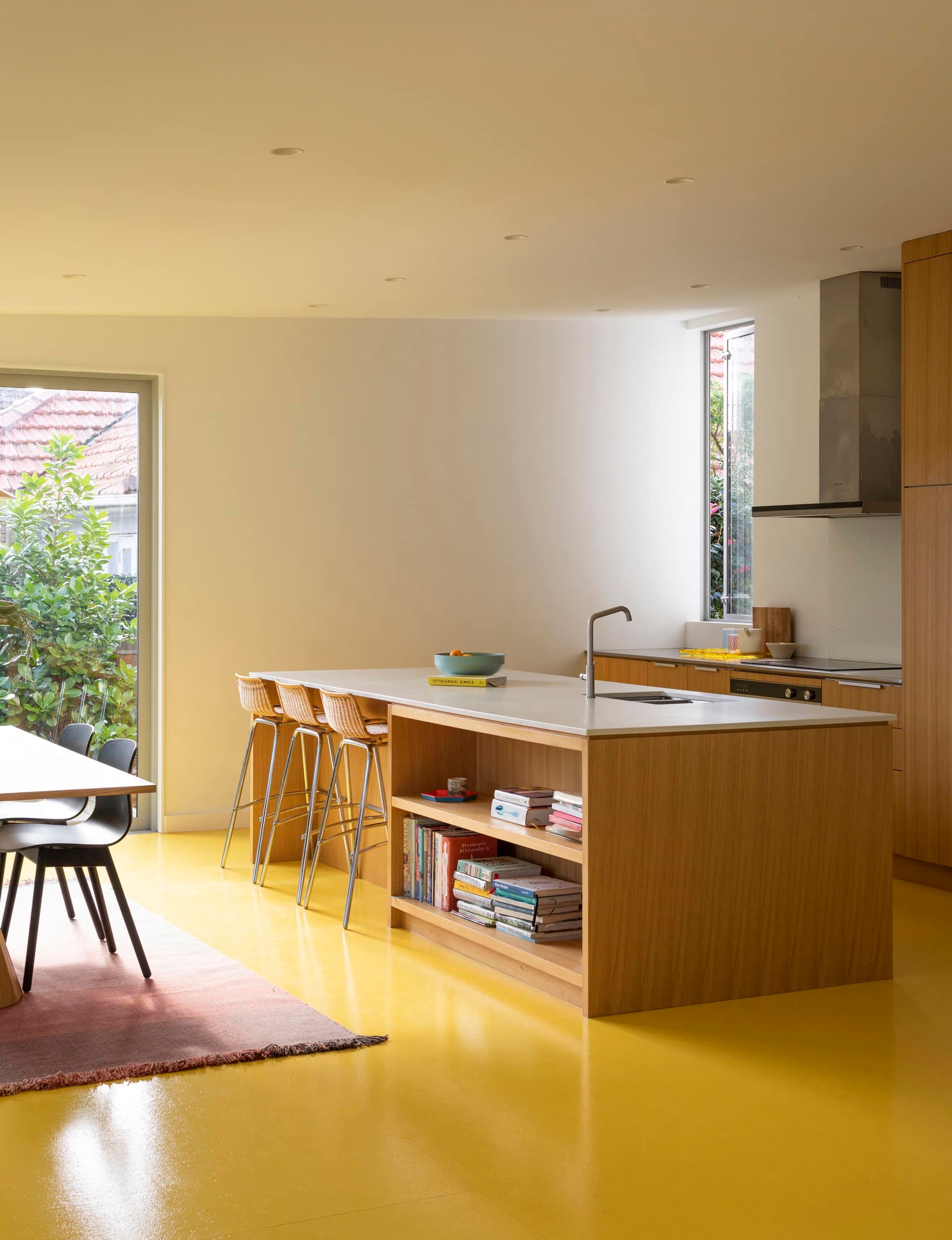Small but modern kitchen with yellow floors and an island with a small built in bookshelf