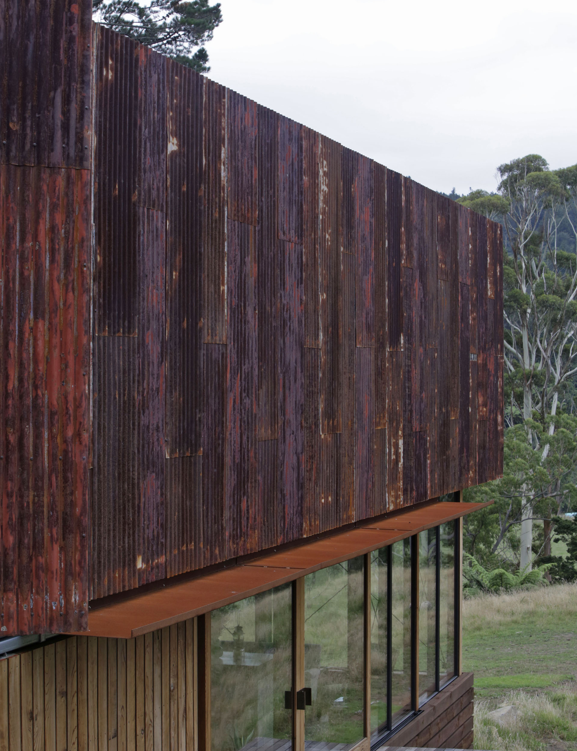 Close up of the rusty corrugated iron roof above large windows on the home