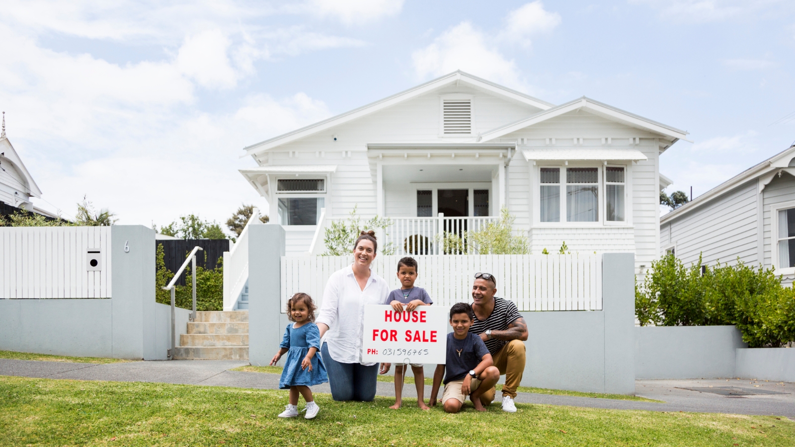 Family sitting in front of sold house. 