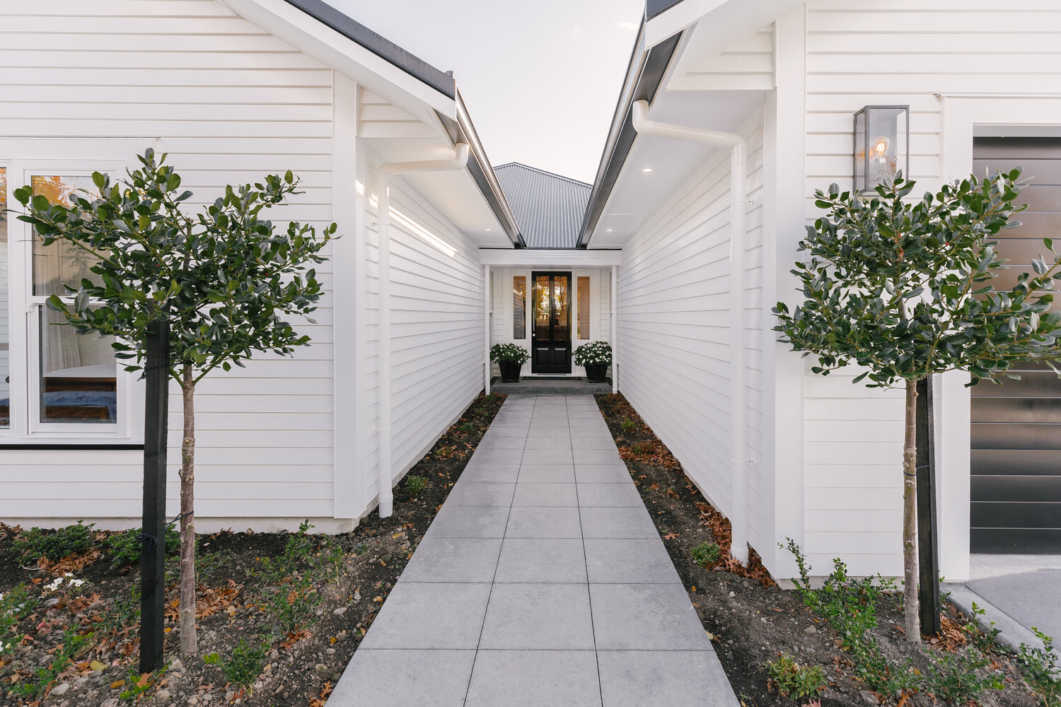 Two white buildings lead the eye to a blue front door at the back of the image.