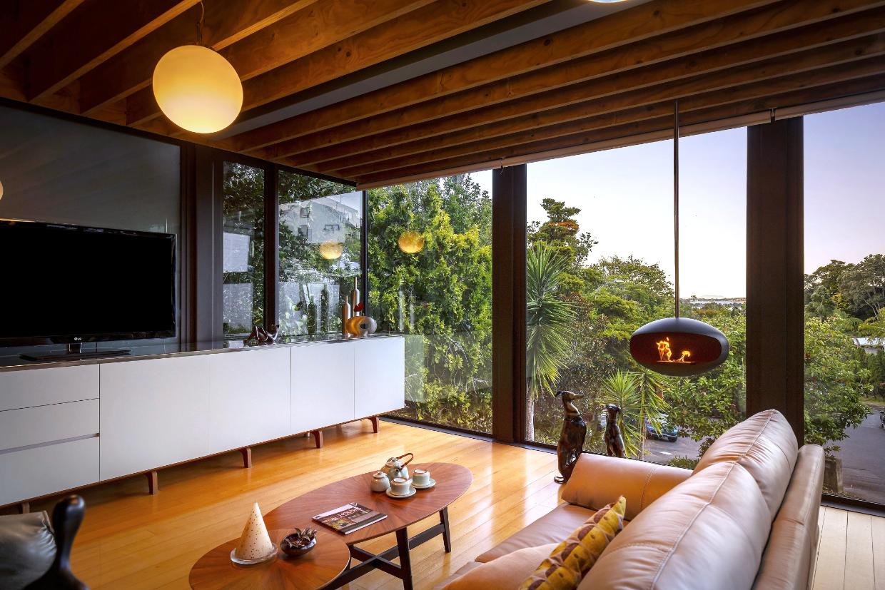 The modern kitchen is anchored by a striking, elongated bench that creates a seamless flow between cooking, living, and the surrounding views.