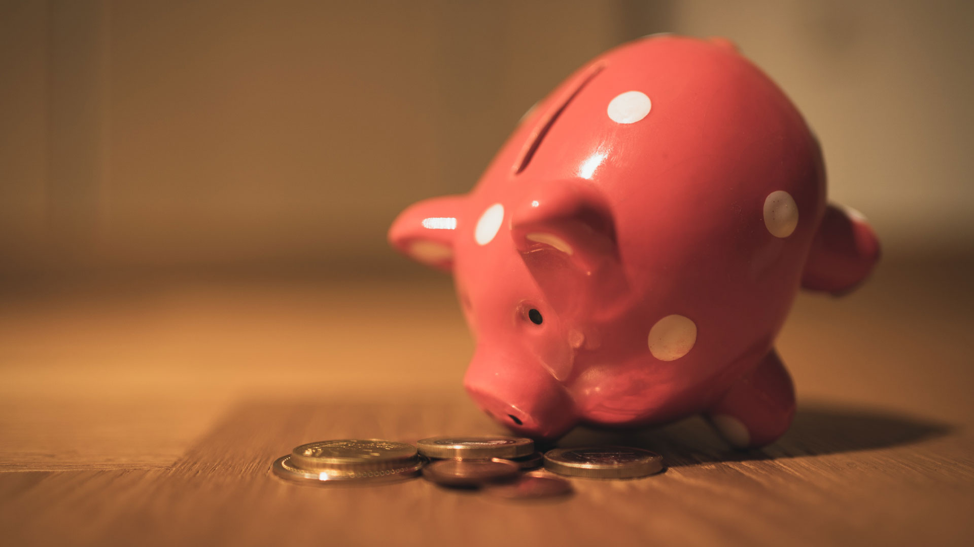 Piggy bank on a table with coins in front of it.