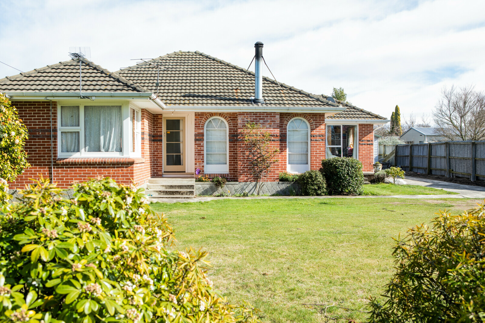 View of a residential brick property with a large front lawn