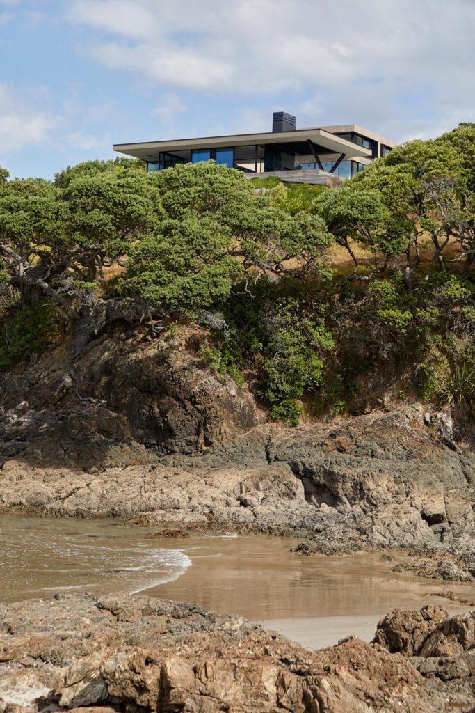 A view of a modern cliff-top home from the beach below.