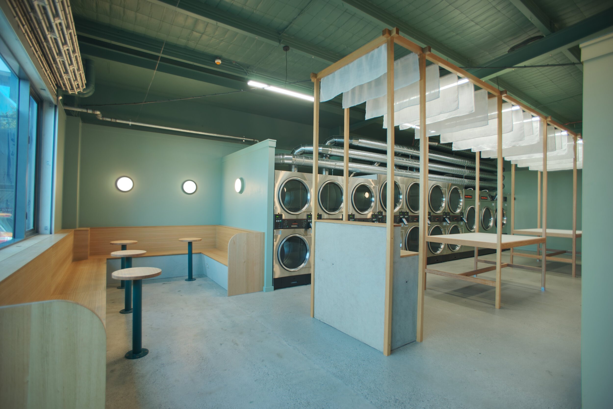 A minimalist laundry room featuring a soft green-blue vintage aesthetic with modern touches, clean lines, and sleek cabinetry.
