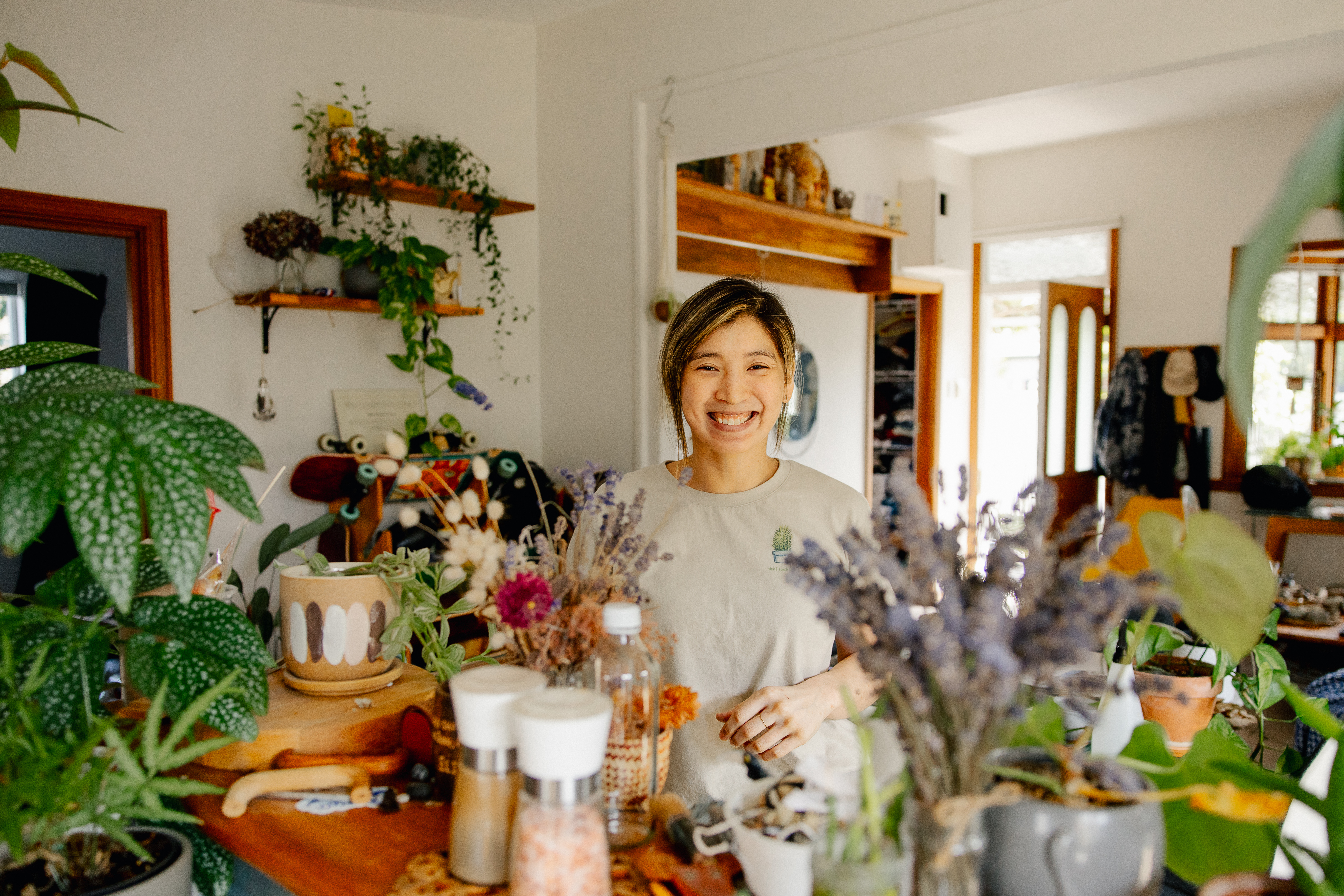 Elissa stands over her kitchen bench which is full of plants