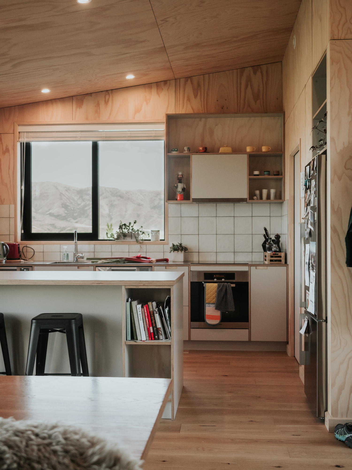 Walls have been built to resemble DOC huts with MDF boards covering the walls of the kitchen. Cookery books fill in gaps on the shelves and the fridge is adorned with images and cuttings. 