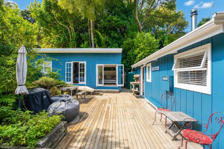 There are decks out both sides of the bach. Pip maintains the garden where they grow their own vegetables. The sleepout and library at the rear was built within a container on skids. Photo: Ray White