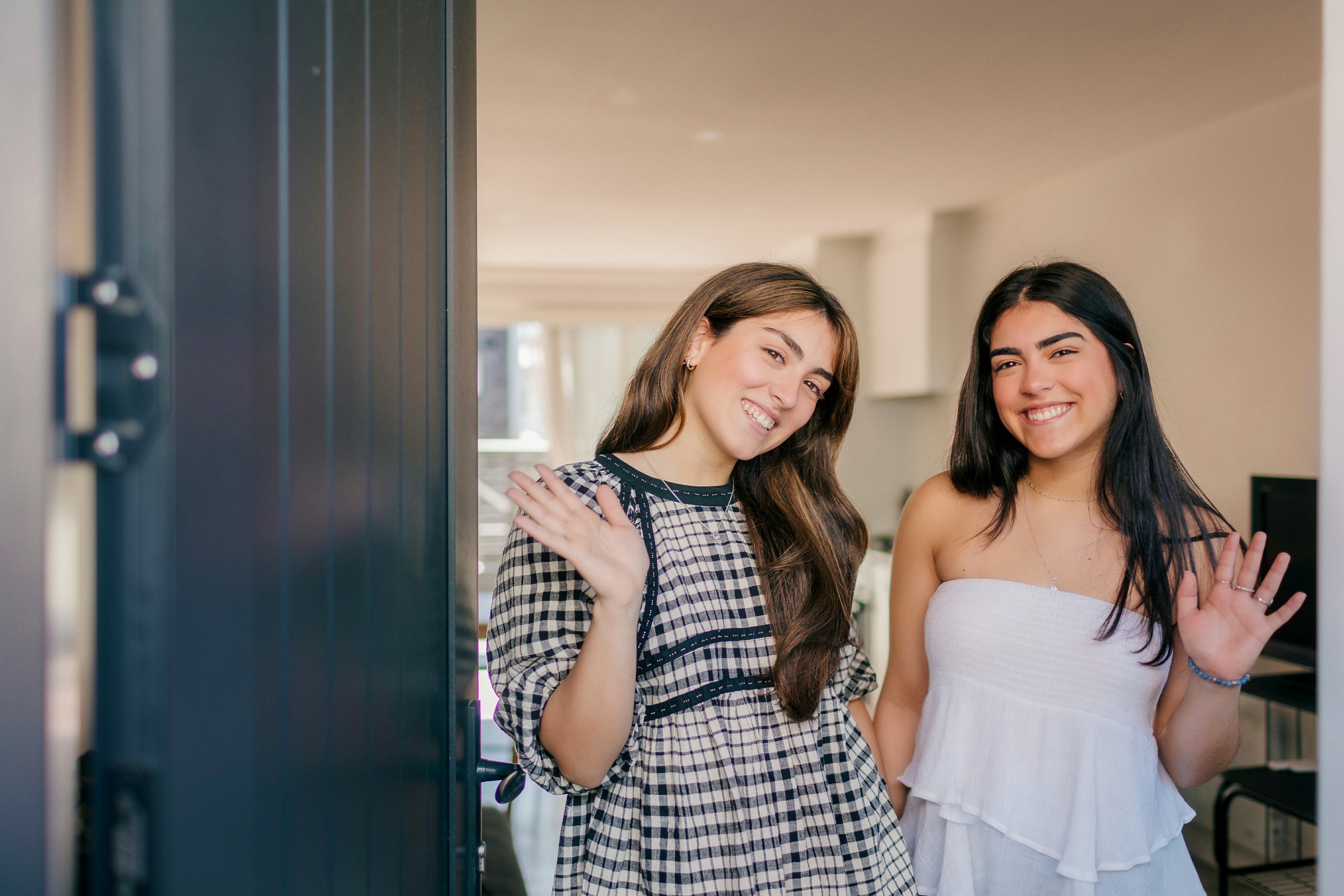 Duda and Bruna waving from inside their front door