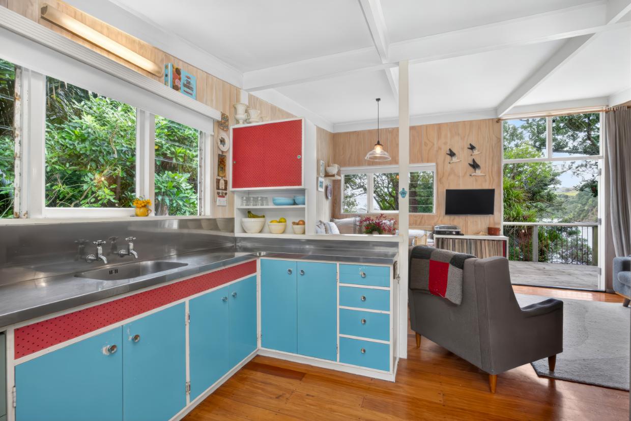 There’s plenty of the original character remaining in the ‘60s bach - even the painted kitchen cupboards and drawers have been retained. Photo: Ray White