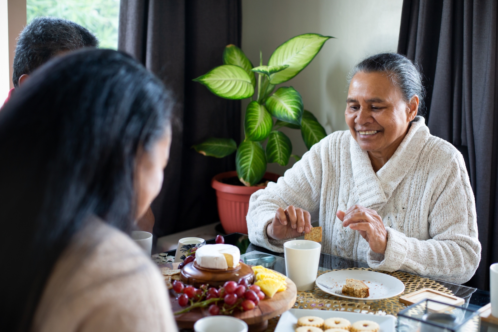 Family gather at the dining table to enjoy a cheese platter