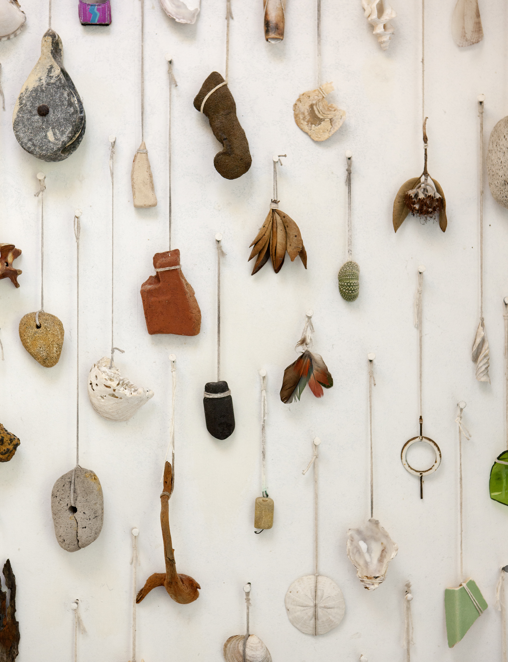 A variety of objects like shells hanging by thread on the wall