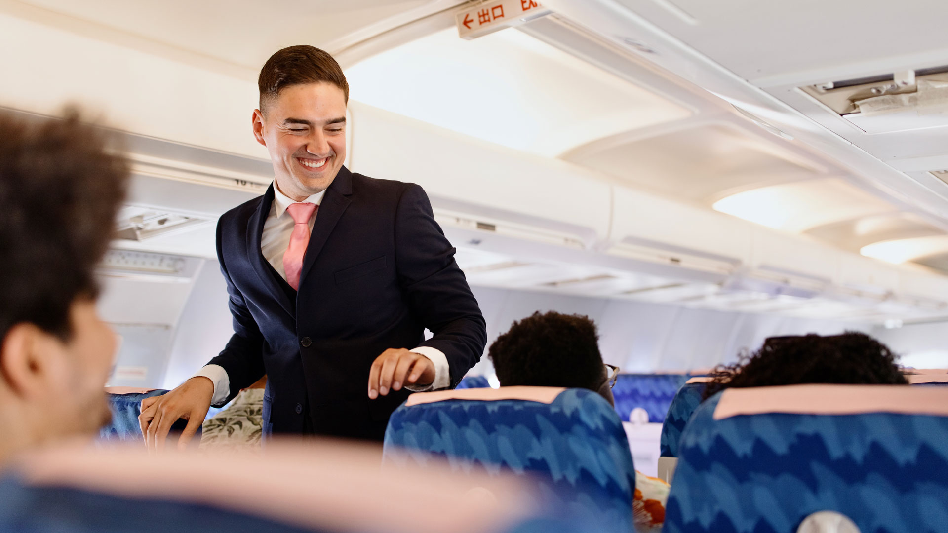 Smiling cabin crew employee interacting with a passenger.