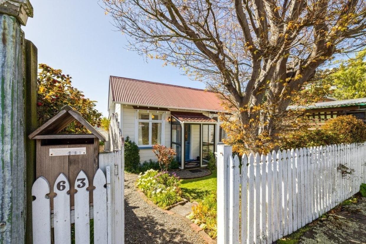 Sumner cottage with white picket fence along the boundary.
