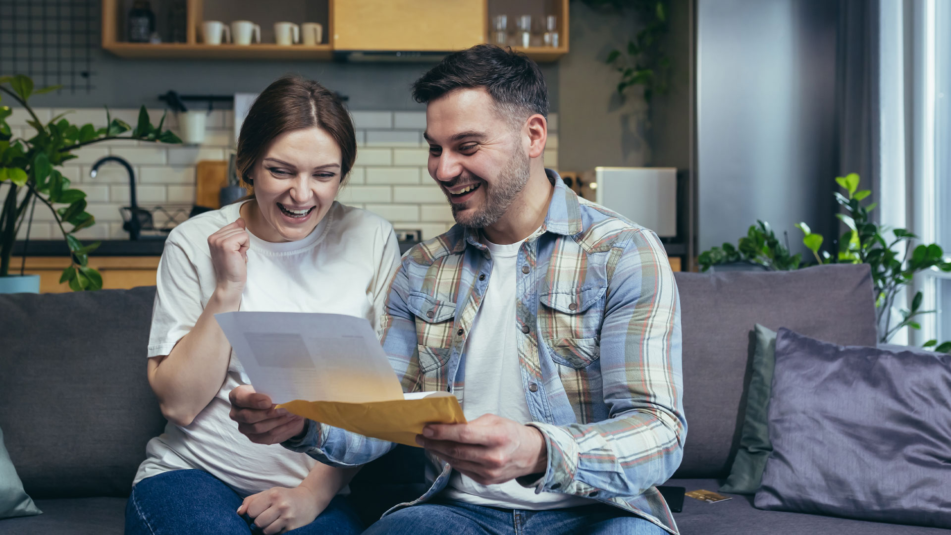 A couple opening a tender offer, and celebrating a high offer on their home.