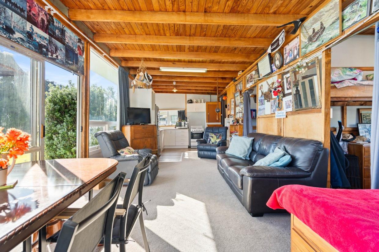 The walls are covered with nostalgic photos and memorabilia. The bach is essentially one large room with bedrooms off this, screened by curtains. Photo: Bayleys