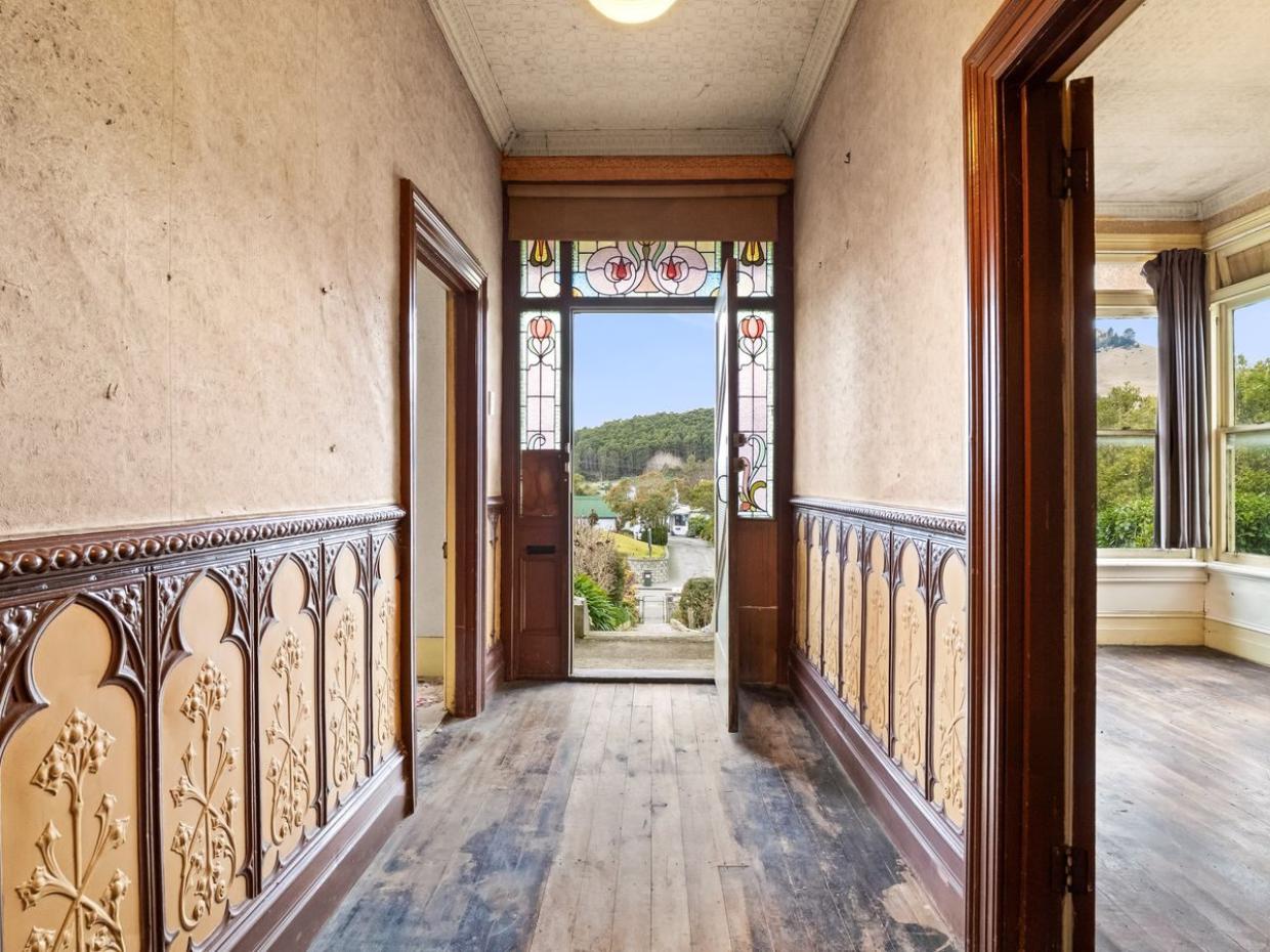 The symmetry continues on the interior with a central hallway embellished with panelling. Photo: BE Real Estate