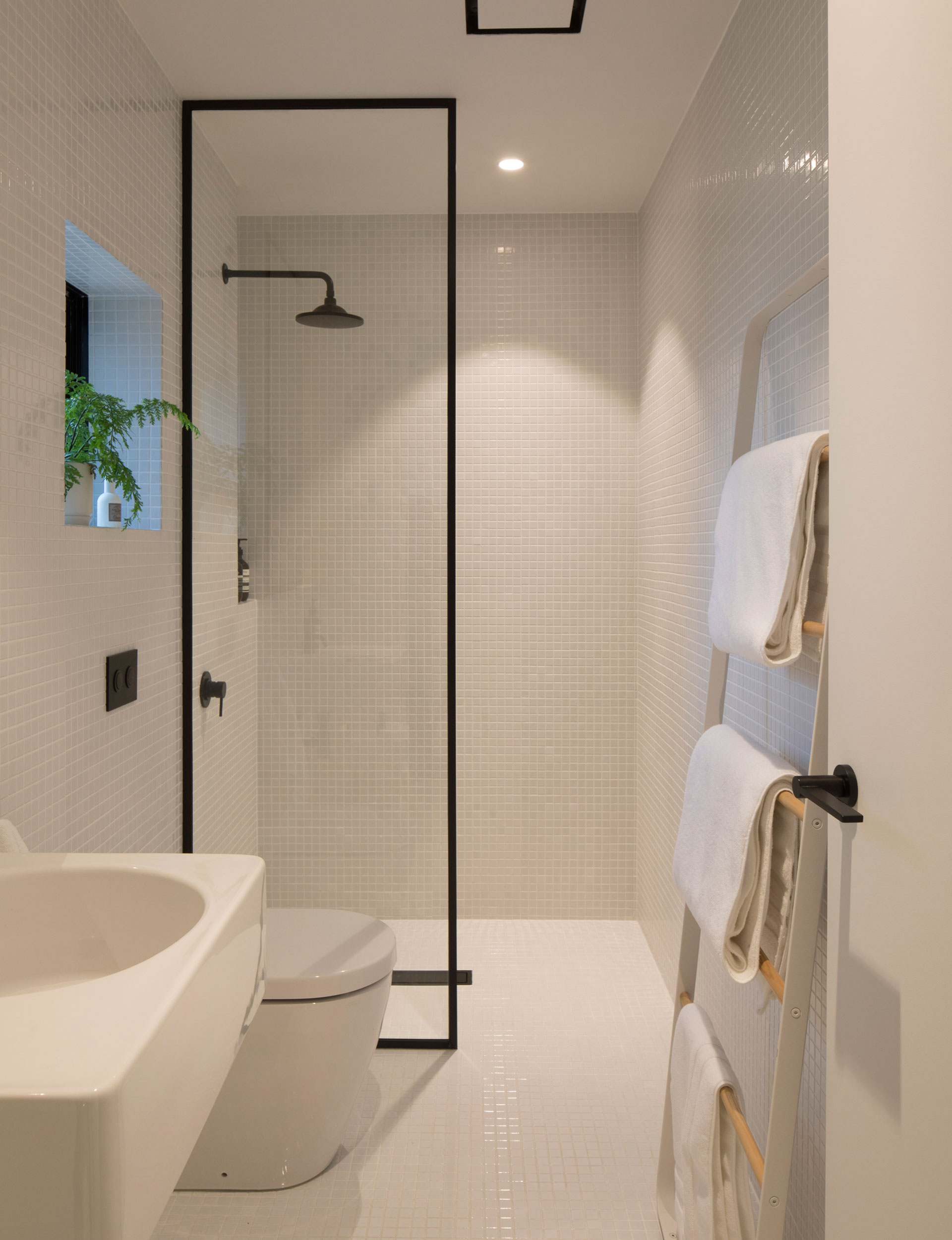 Floor to ceiling tiles and refined function create a generous feeling of space in this minimalist bathroom.  Photo above : Patrick Reynolds