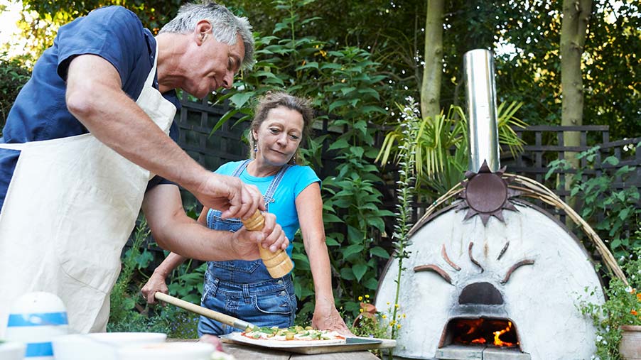 Man and woman prepare pizza for outdoor pizza oven