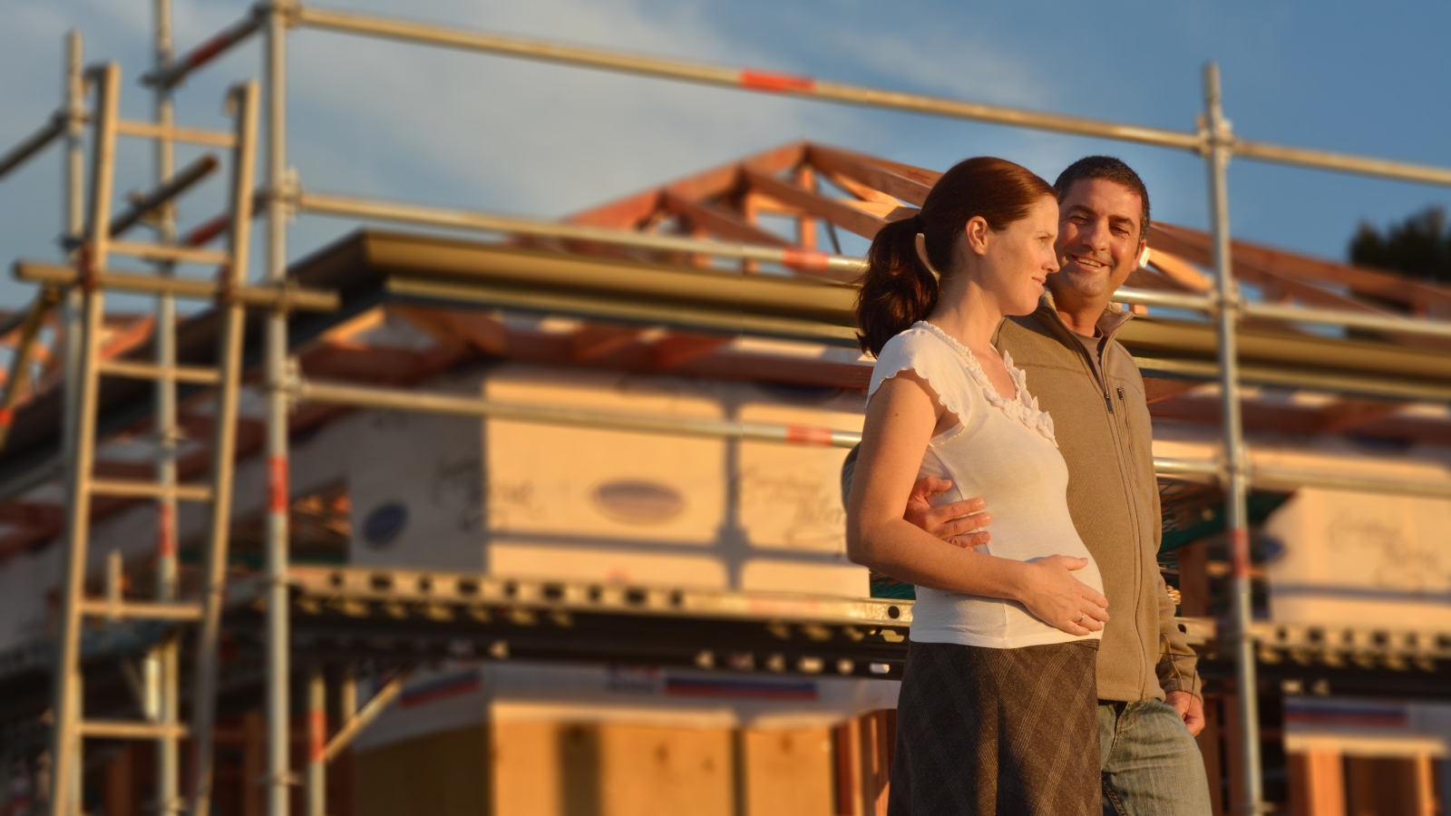 Couple standing in front of home under construction. 