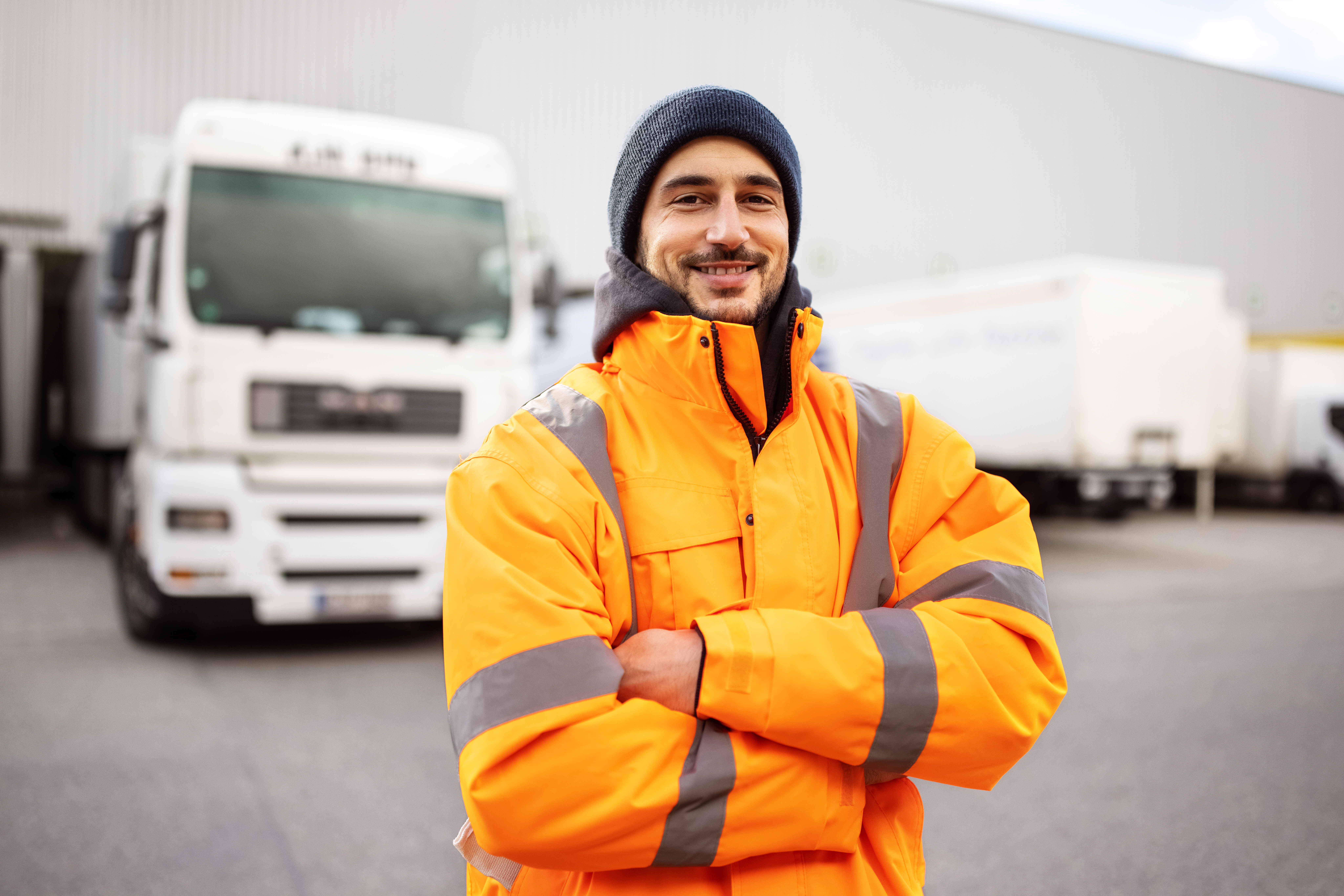 Male truck driver standing in front of truck. 