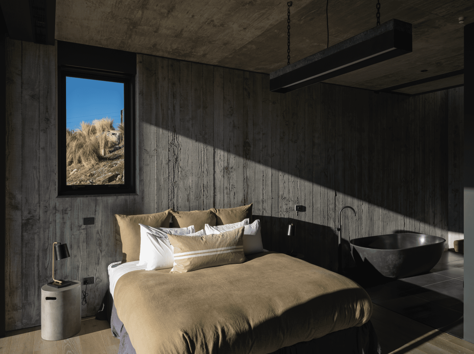 Board-formed concrete provides textural interest and anchors the colour scheme in this minimal master bedroom suite, which exudes a sanctuary-like calm. Image: Simon Devitt