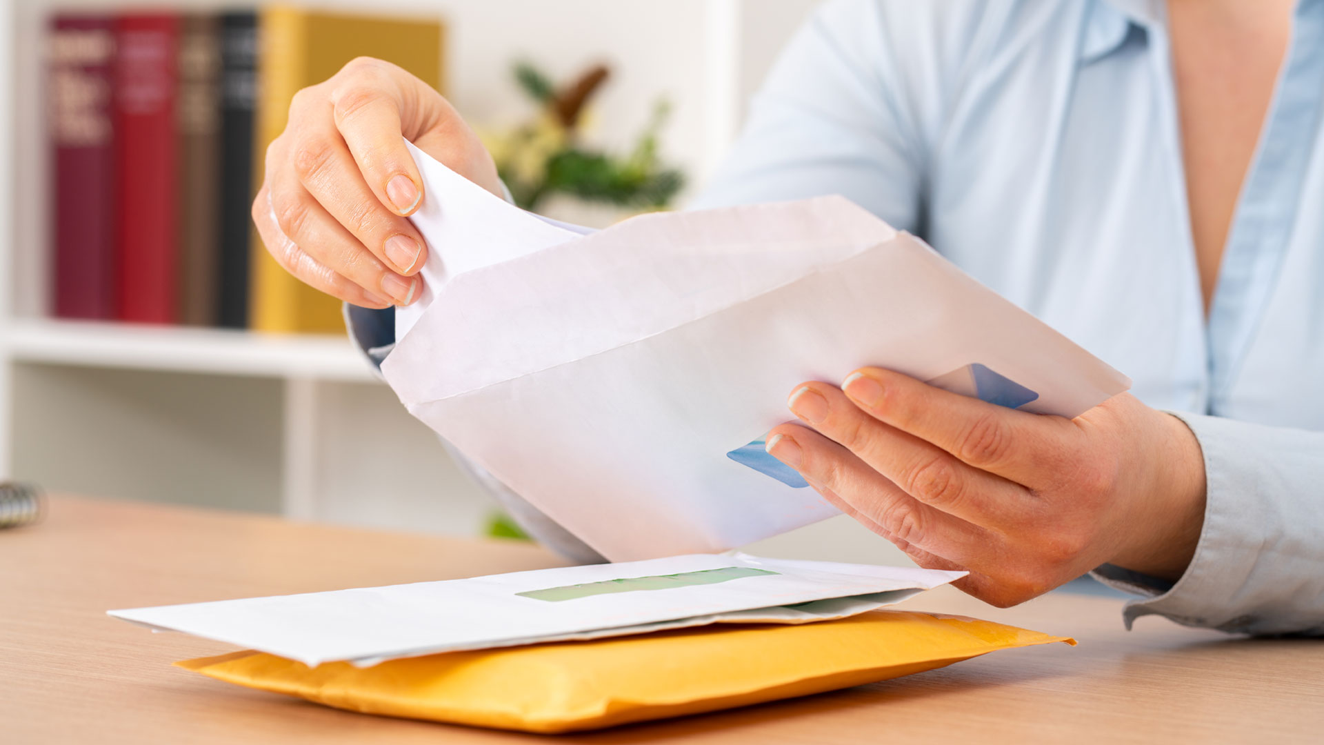A home seller opening an enevelope containing a tender offer for her home.