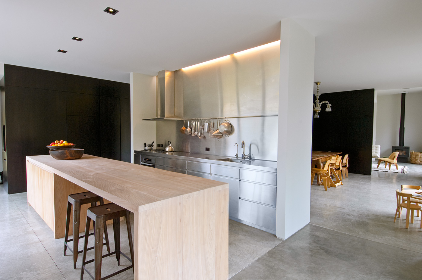 A modern kitchen featuring a sleek stainless steel splashback. The splashback covers the wall behind the countertop, reflecting the under-cabinet lighting and enhancing the clean lines of the space. It complements the minimalist design, with its reflective surface adding depth and a touch of elegance to the kitchen’s overall aesthetic