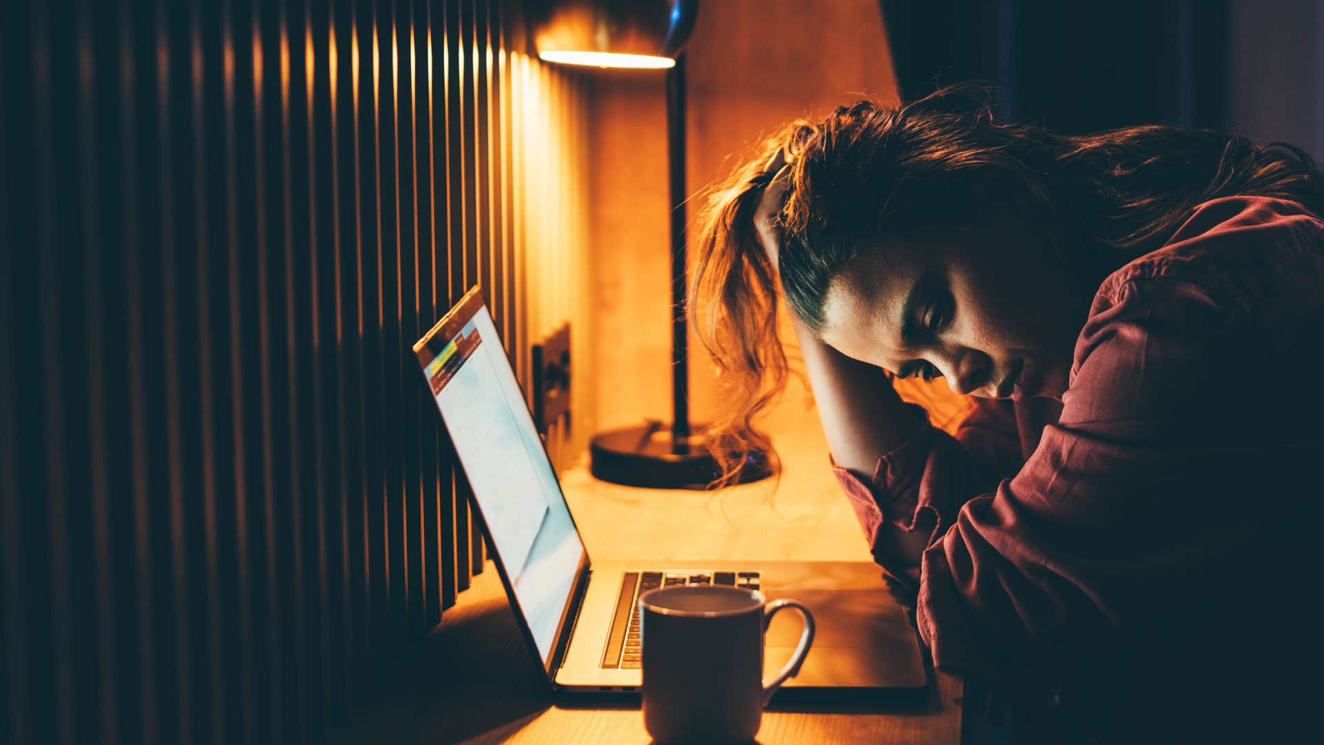 Stressed out woman searching for jobs on her laptop late at night.