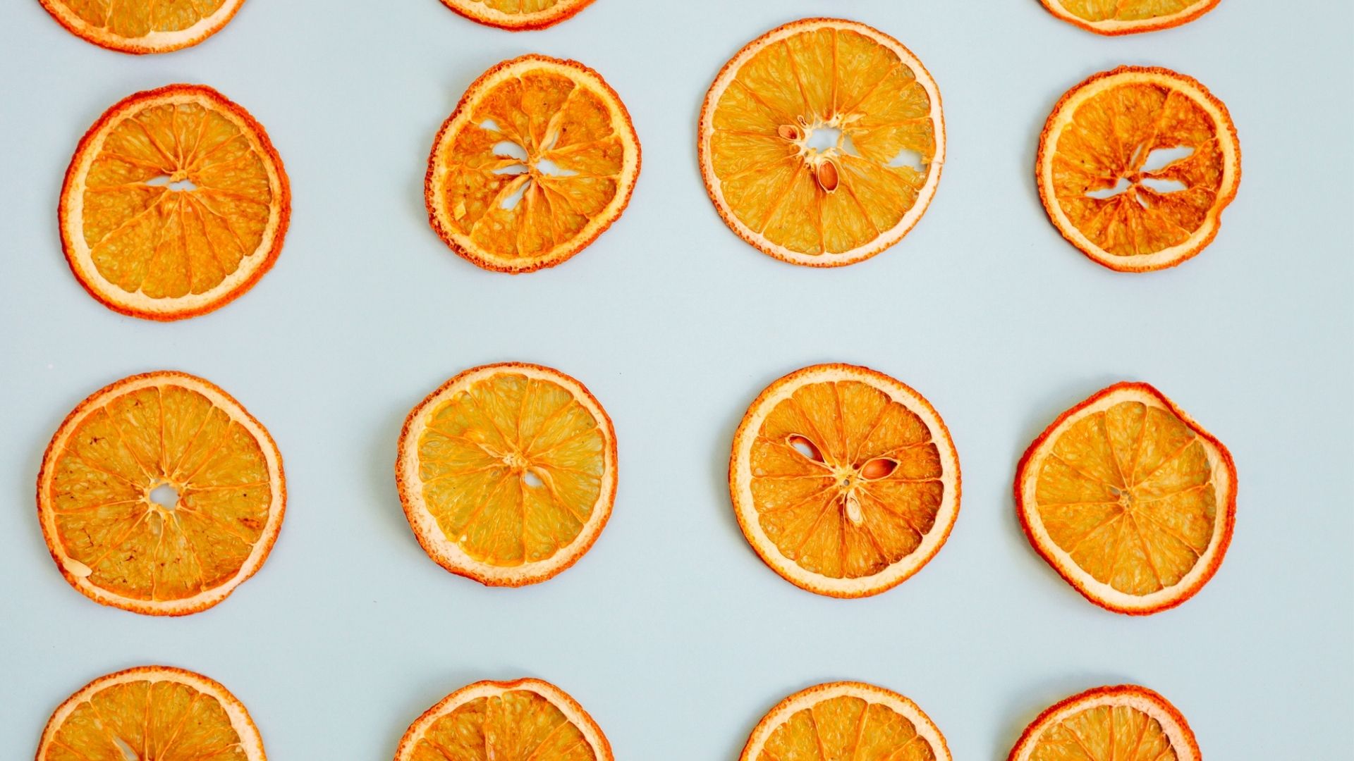 Slices of orange that have been dehydrated are on a grey background.