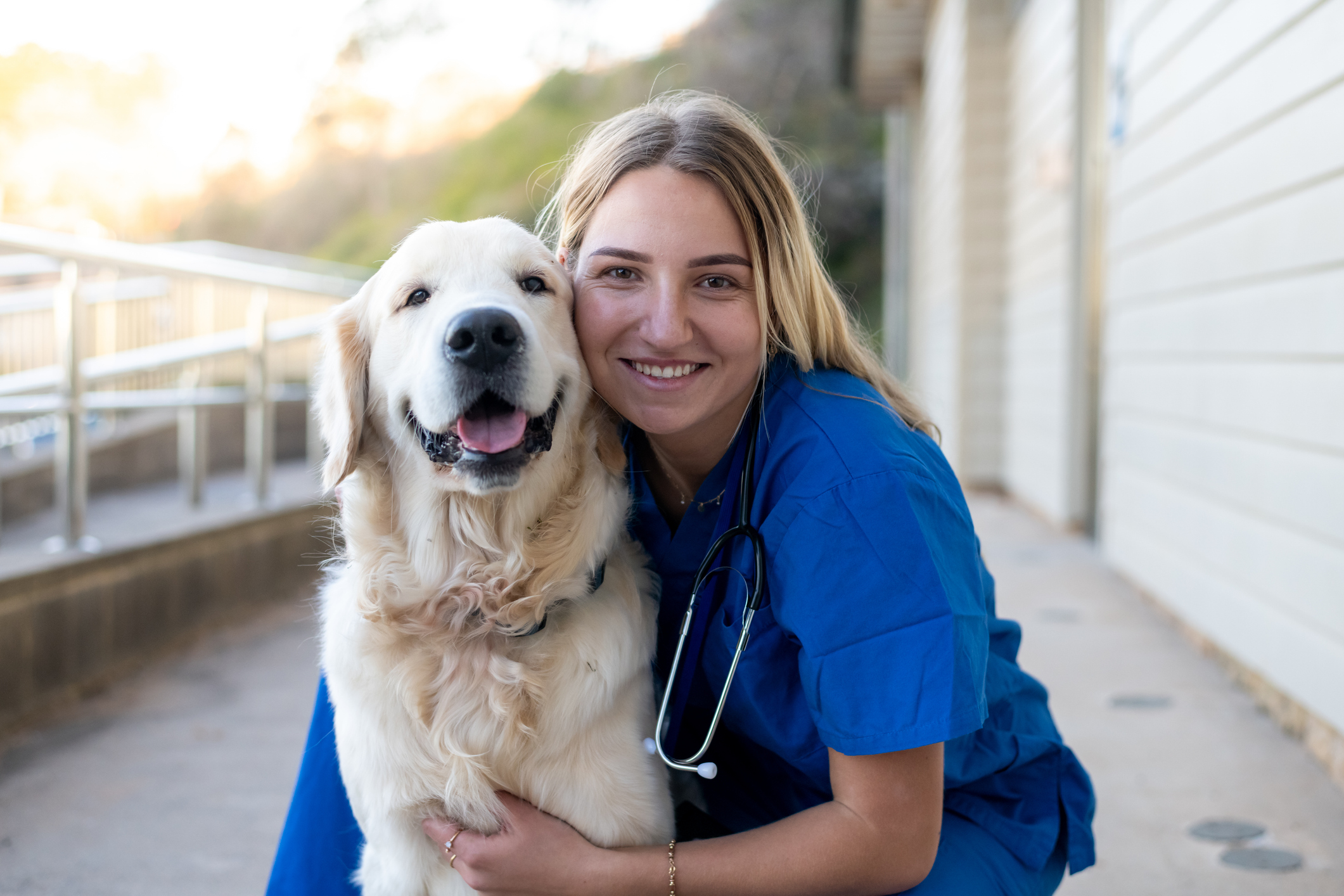 Female vet nurse with golden retriever outside of vet clinic