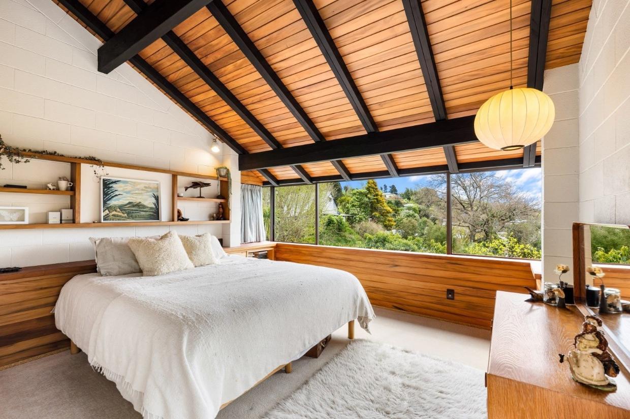Sarking and dark-stained beams bring plenty of visual drama to the main bedroom suite. This room opens to a small deck.
