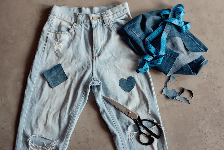 Jeans layed out on the floor with pieces of denim in hearts about to be sewn on.