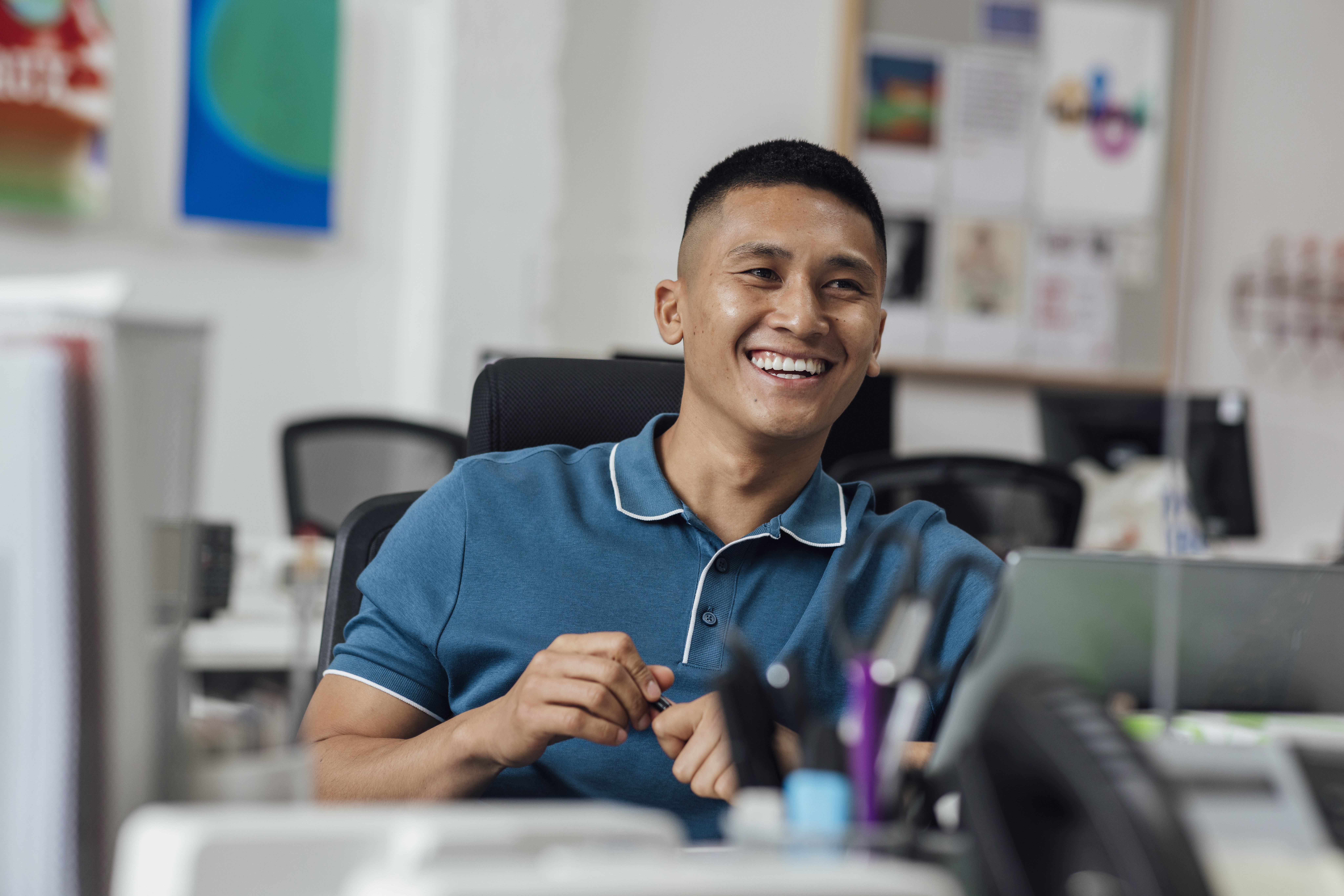 Male teacher sitting in classroom with smile on face