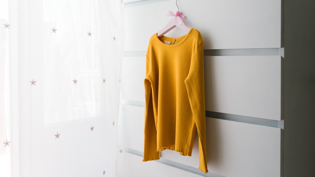 A secondhand women’s jumper hanging on a coat hanger ready to be photographed so it can be sold online.