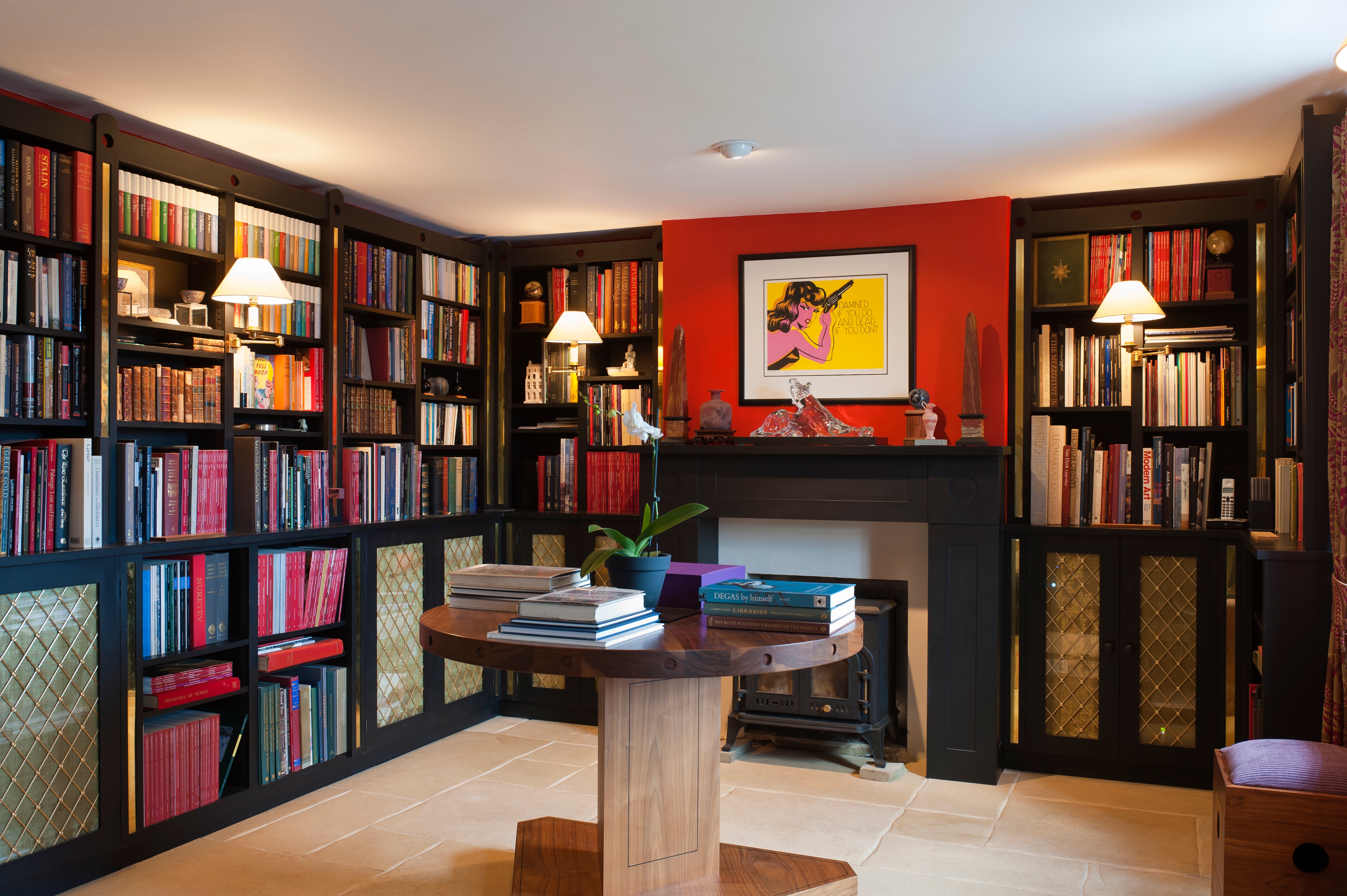 Moody library with red paint and dark wood and walls lined with books.