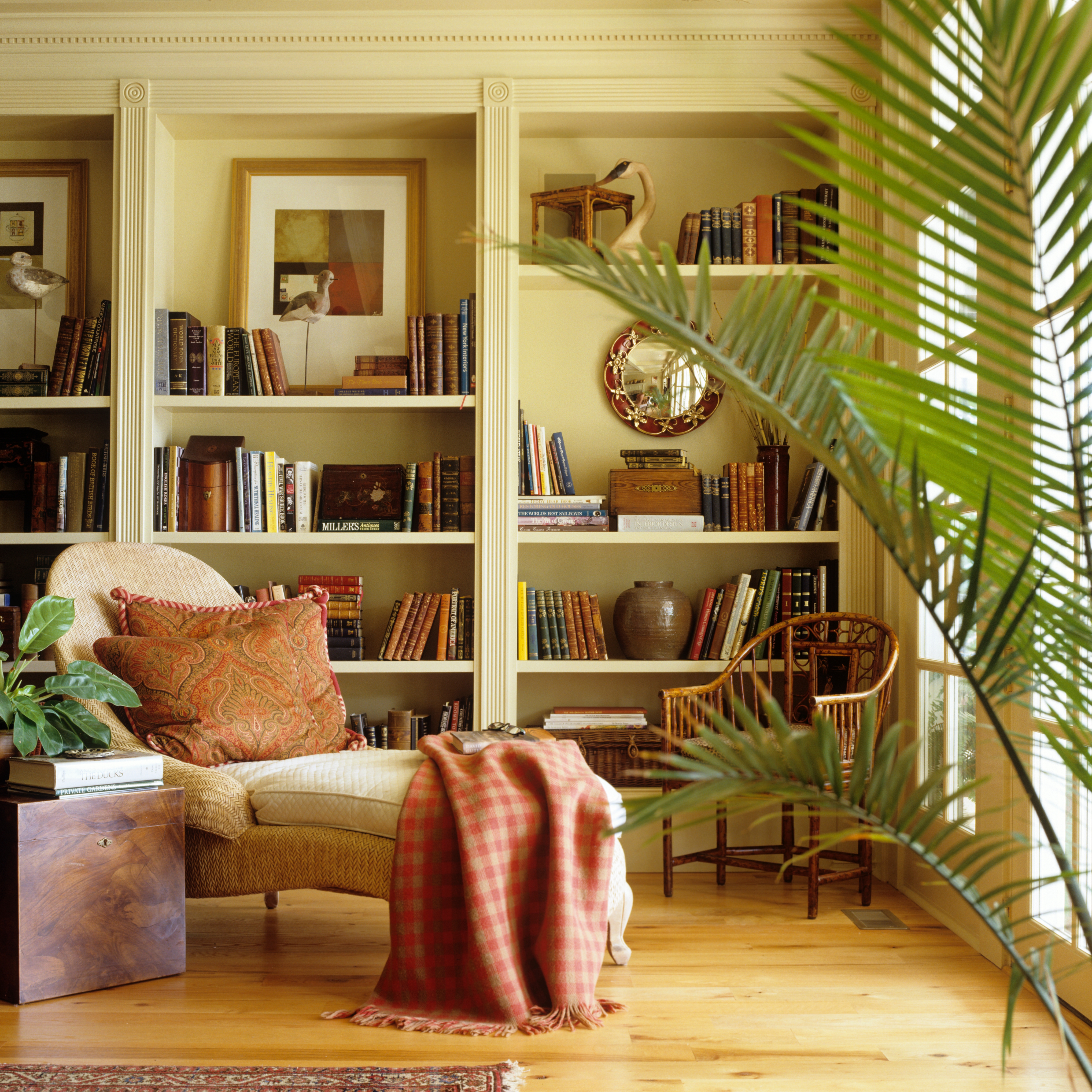 Cream coloured in-built bookcase in a traditional interior with chaise longue 