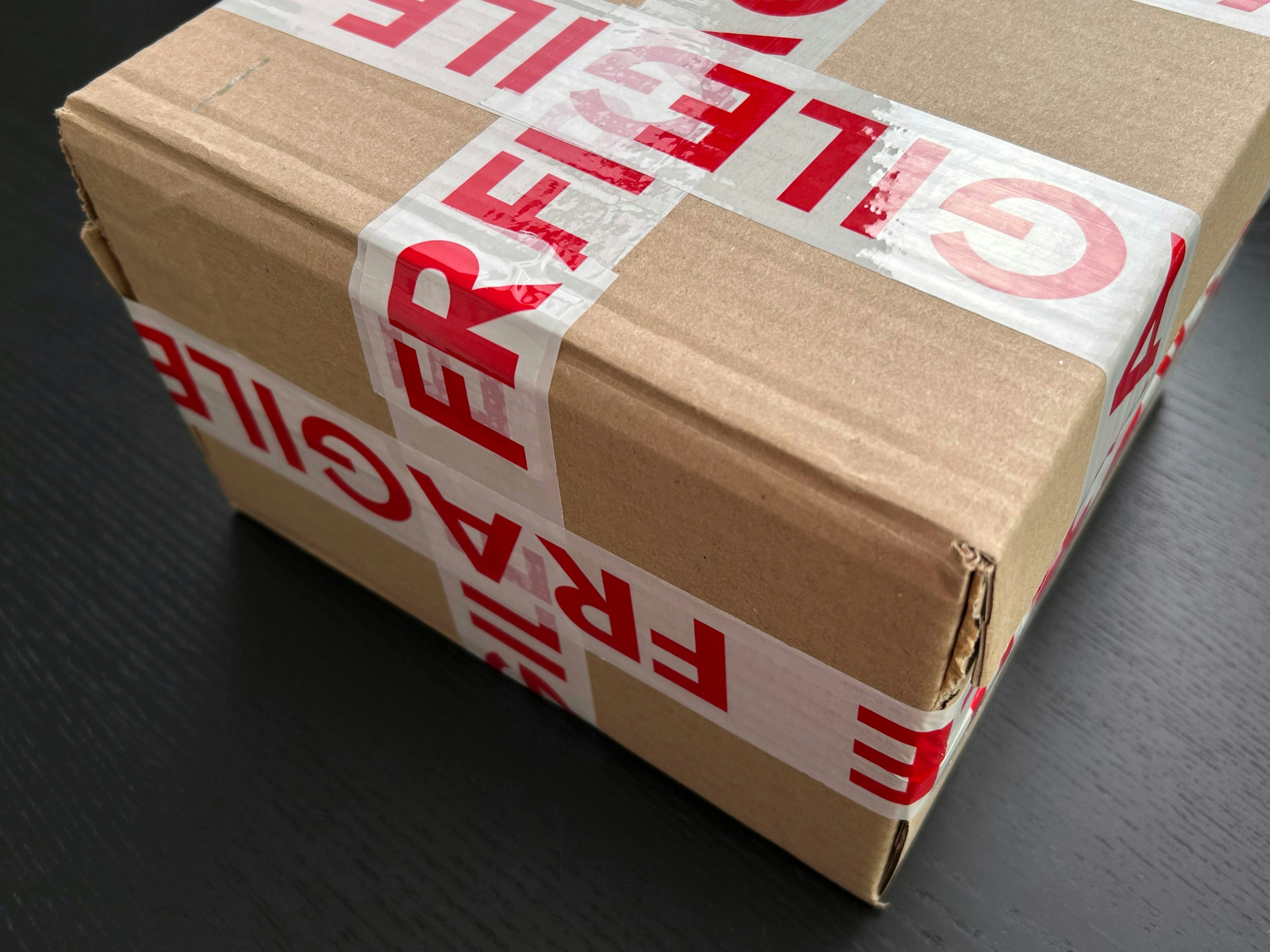 A package covered in brown paper and fragile tape. 
