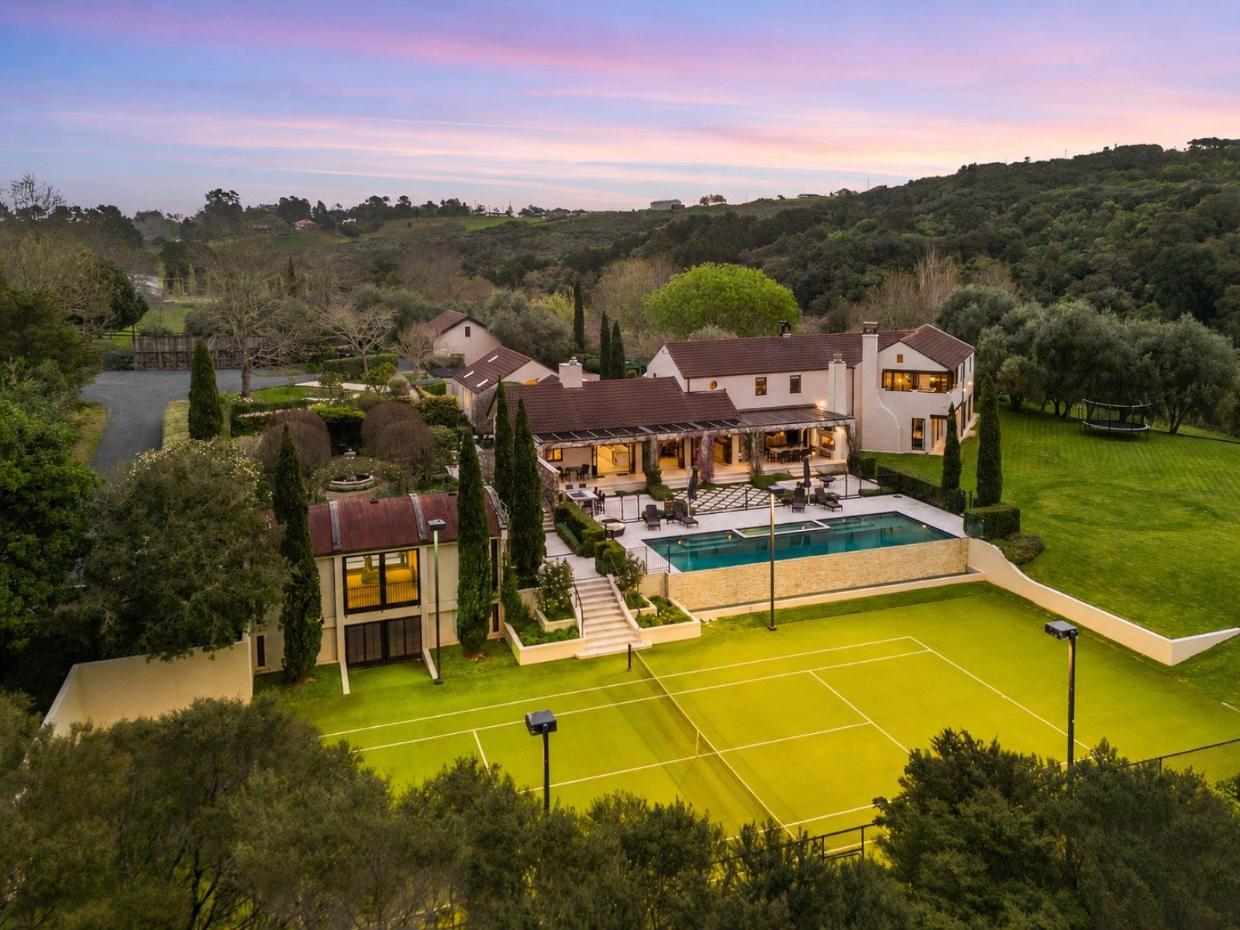Mansion with a large tennis court and helipad field.