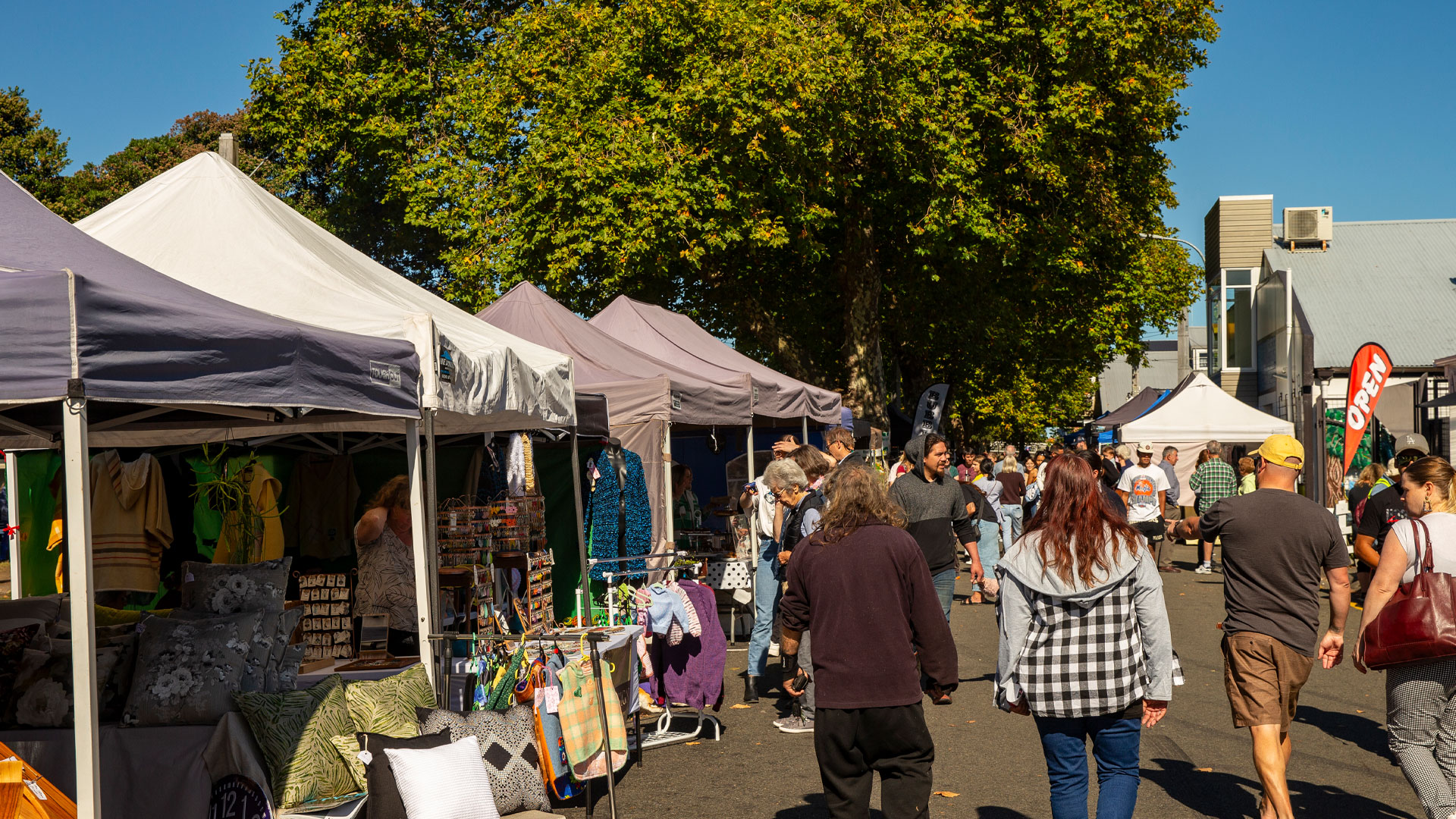 A market in the town of Whanganui with people walking by the stalls.