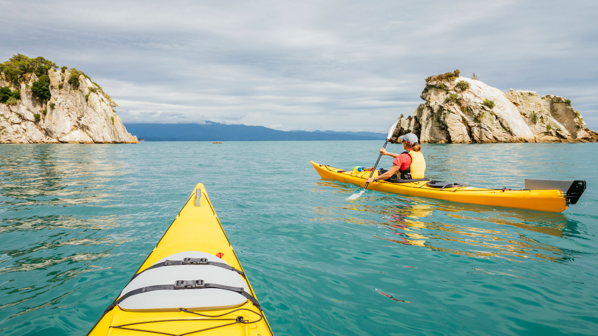 Point of view photograph showing a yellow kayak on the waters of the Abel Tasman in New Zealand.