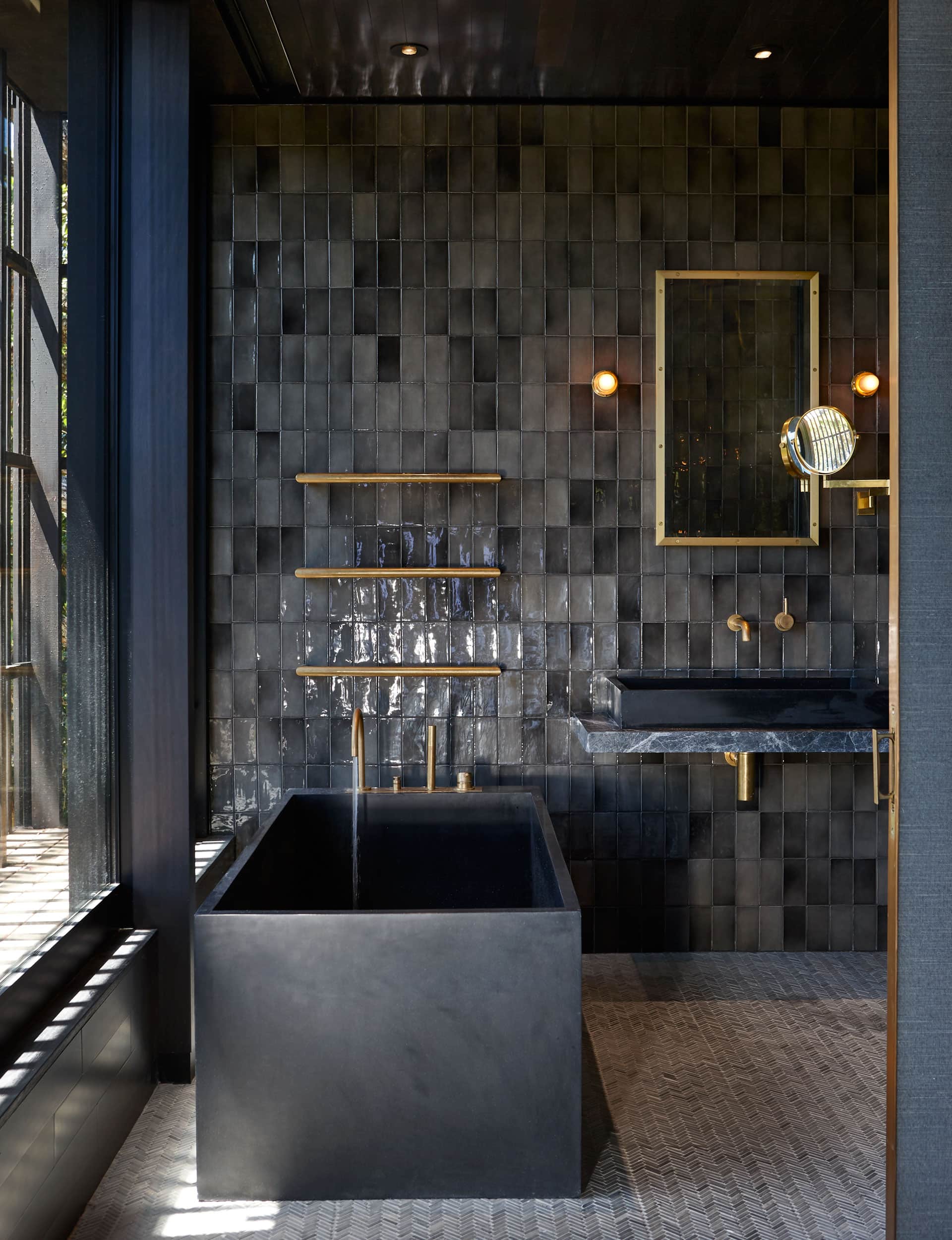 Bathroom in a Waiheke home by Herbst Architects, featuring a smoky color palette paired with brass fittings for a masculine, moody atmosphere.