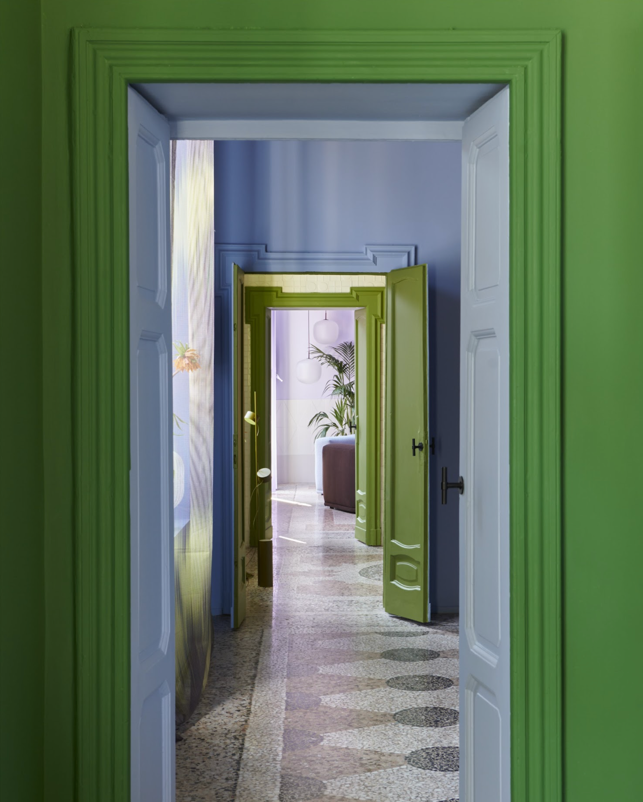 Green door frame leads to a corridor with green doors and marble floors