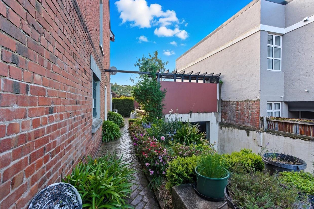 Flowers and hedging lines the pathway at the side of the house.