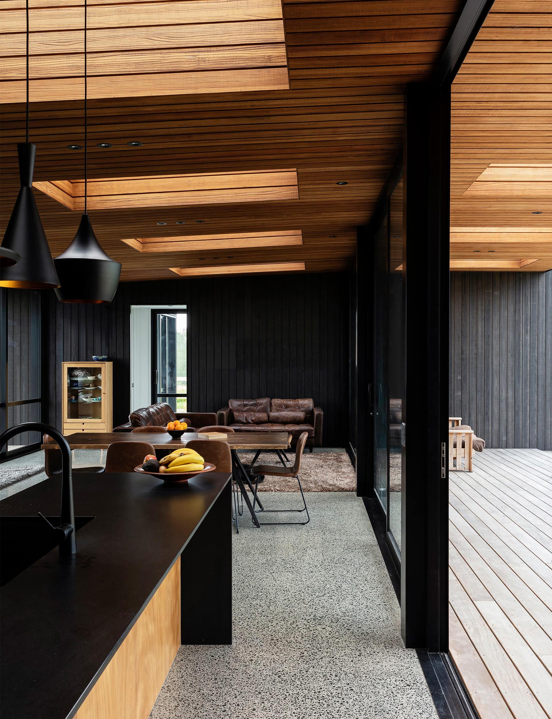 As well as being in harmony with the dark-stained exterior, the framing functions beautifully with interior details, such as the black waterfall kitchen island – a feature in the open-plan living area – and black flecks in the polished-concrete floor.